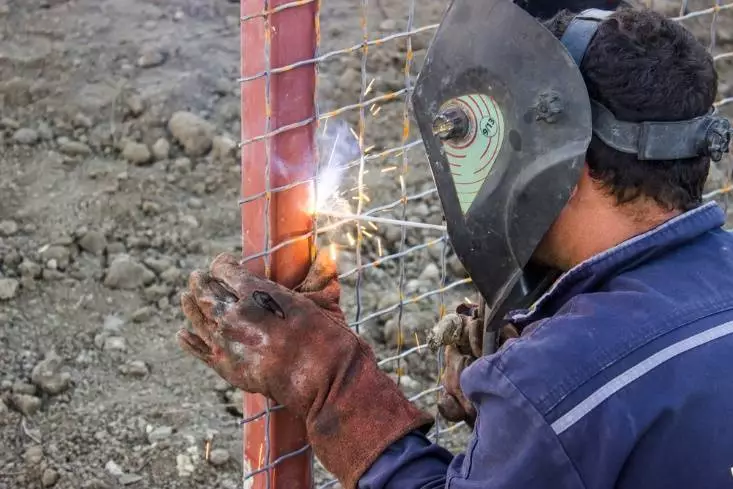 Welding fence panels to a post.